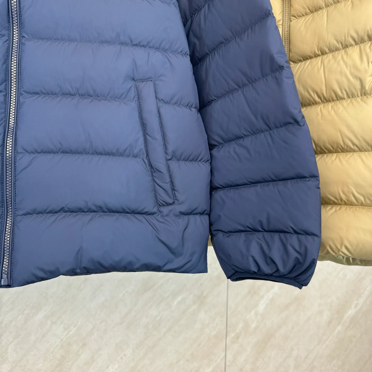 P930 lightweight down jacket size s m l xl Nylon fabric has good windproof and waterproof properties, which can effectively block the intrusion of wind and rain from the outside and keep the inside dry, suitable for wearing in humid or rainy environments.  The red label on the chest is made with an imported MECLO embroidery machine. The original pattern is scanned first, and then high-quality silk thread is used to make a pattern. The density effect is adjusted by continuous pattern making.  Exquisite details: the zipper design is simple and elegant, easy to operate; the closing design of the cuffs and hem effectively prevents the intrusion of cold wind, improving the warmth and comfort of wearing.  High-quality filling: 90 white duck down is selected, with a weight of 260g, ensuring excellent thermal insulation performance. After strict screening and processing, the velvet is not easy to drill, ensuring durability. The hangtags, wash marks, air holes, and four-button buttons are all customized from the original one-to-one mold.
